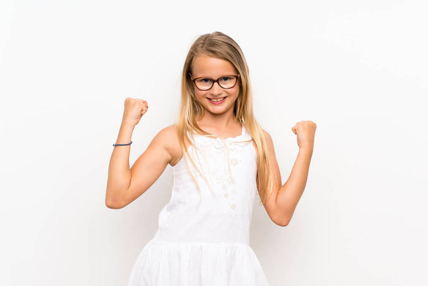 Маленька дівчинка над ізольованою білою стіною робить жест перемоги
 - Фото, зображення