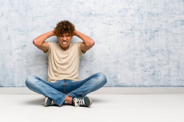Jeune homme afro-américain assis sur le sol frustré et prend les mains sur la tête
 - Photo, image
