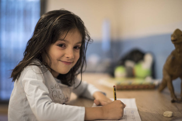 Pieni tyttö 6-vuotias tekee kotitehtäviä kotona huoneessaan
 - Valokuva, kuva
