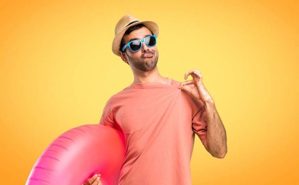 Man with hat and sunglasses on his summer vacation proud and self-satisfied in love yourself concept on orange background - Photo, Image