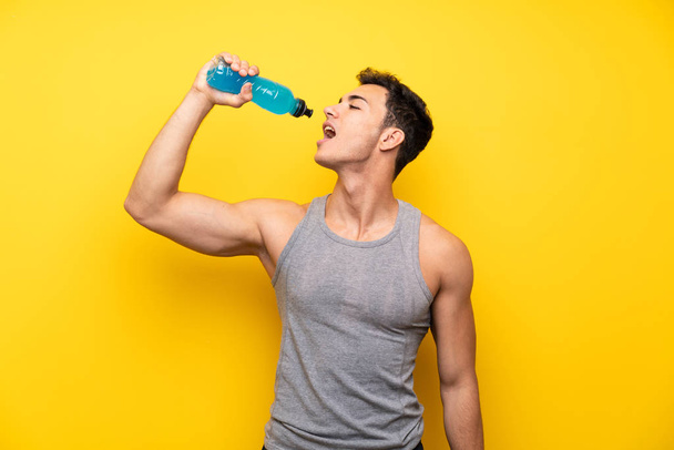 Красивий спортивний чоловік над ізольованим тлом з пляшкою содової
 - Фото, зображення
