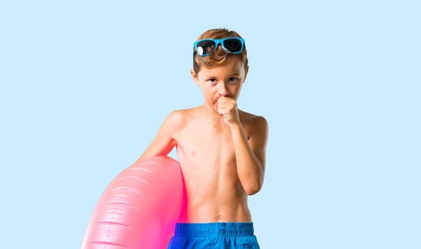 Kind op de zomervakantie lijdt met hoest en slecht gevoel op geïsoleerde blauwe achtergrond - Foto, afbeelding