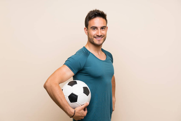 Handsome sport man over isolated background holding a soccer ball - Valokuva, kuva