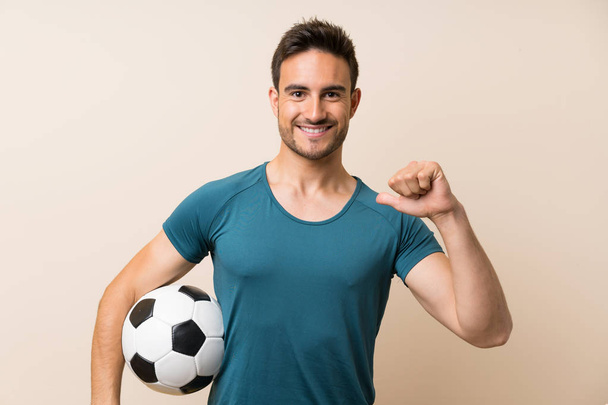 Bonito homem esporte sobre fundo isolado segurando uma bola de futebol
 - Foto, Imagem