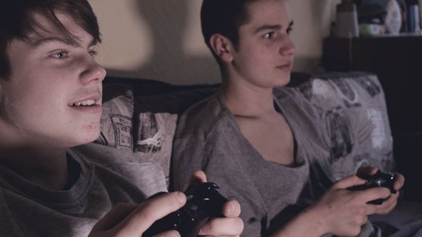 Dos amigos (chicos) juegan a la consola de videojuegos, se divierten, ríen, sostienen el joystick
. - Foto, imagen