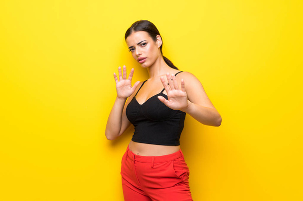 Young woman over isolated yellow background nervous stretching hands to the front - Fotografie, Obrázek