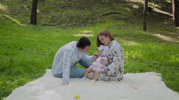 Mutlu aile anne ve baba yatak örtüsü üzerinde bebek ile oynarken. - Video, Çekim