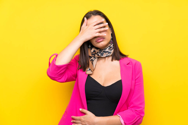 Young woman over isolated yellow background covering eyes by hands - Photo, Image