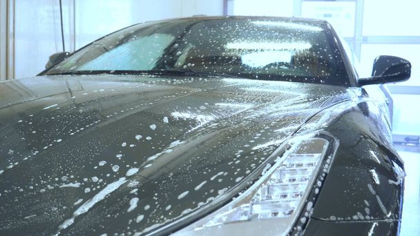 Человек в специальном костюме полирует тело серого автомобиля, инструмент для полировки автомобилей, в мастерскую
. - Фото, изображение