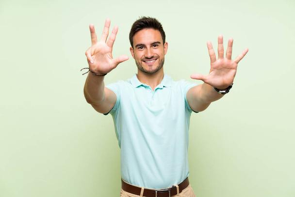 Knappe jonge man over geïsoleerde achtergrond tellen negen met vingers - Foto, afbeelding