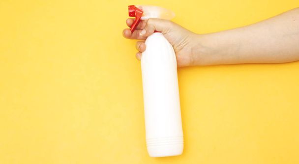 Nahaufnahme Hand hält Reinigungsflasche auf gelbem Hintergrund Seitenansicht. professionelle Reinigungsprodukte, Frühjahrsputz. Haushaltschemie - Foto, Bild
