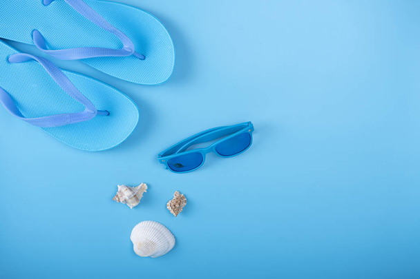 Flip-flops, sunglasses and sea shell on blue background - Photo, Image