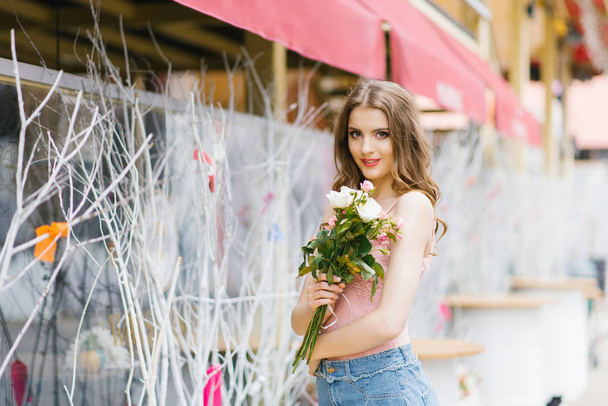 young cute girl with a professional make-up and twisted hair holding a bouquet of flowers. Copy space - Foto, imagen