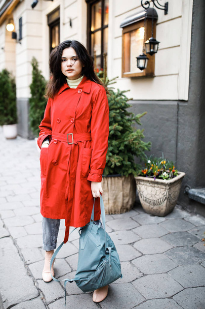 schöne brünette junge Frau trägt einen Mantel und geht auf der Straße - Foto, Bild