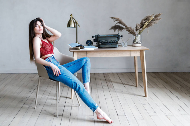 Linda joven - morena en ropa interior hermosa y jeans de pie en el escritorio
 - Foto, Imagen