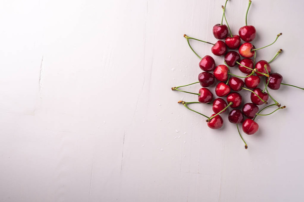 Copy space cherry berries with stem on wooden white background and water drops top view - Photo, Image