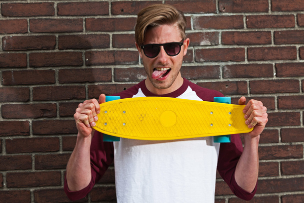 Mode urbaine skateboarder avec des lunettes de soleil posant en face de br
 - Photo, image