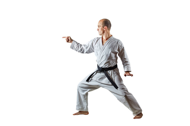 Volwassen atleet met een zwarte gordel treinen formele Karate oefeningen op een witte geïsoleerde achtergrond - Foto, afbeelding