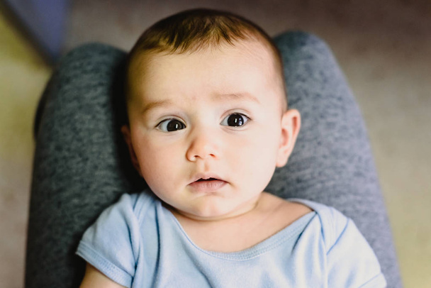 Portrait du visage rond d'un bébé sur les jambes de sa mère
. - Photo, image