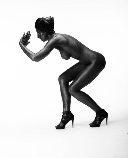 Naked woman painted in black on a white background in the studio - Photo, image