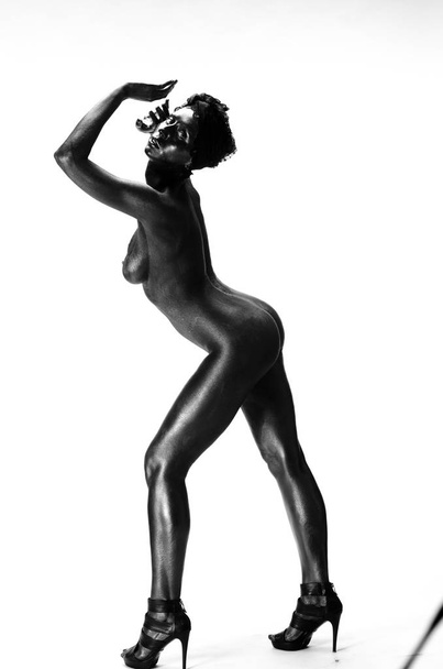 Naked woman painted in black on a white background in the studio - Photo, Image