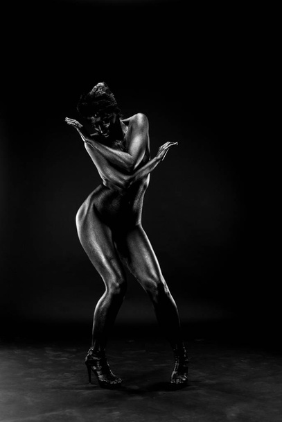 Naked woman painted in black on a white background in the studio. - Foto, afbeelding