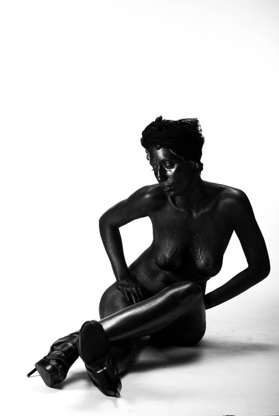 Naked woman painted in black on a white background in the studio - Foto, Imagem