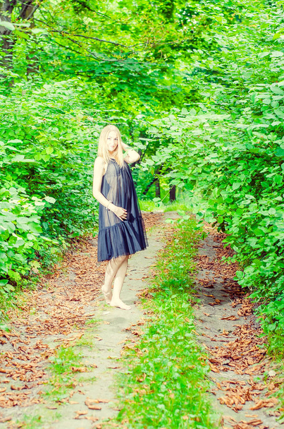 Ritratto di una bella ragazza con gli occhi azzurri in una giacca grigia nel campo tra alberi e erba alta e asciutta, tinta di grigio
  - Foto, immagini