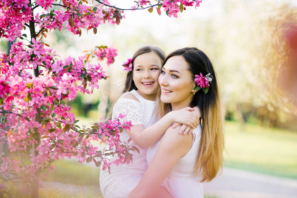 Close-up portret van zachte zachte moederschap ouderschap voelen tevreden ben blij te hebben vrije tijd warm en gezellig te knuffelen de aanraking van een hand om stijlvolle witte kleding te dragen in het voorjaar van bloemen - Foto, afbeelding