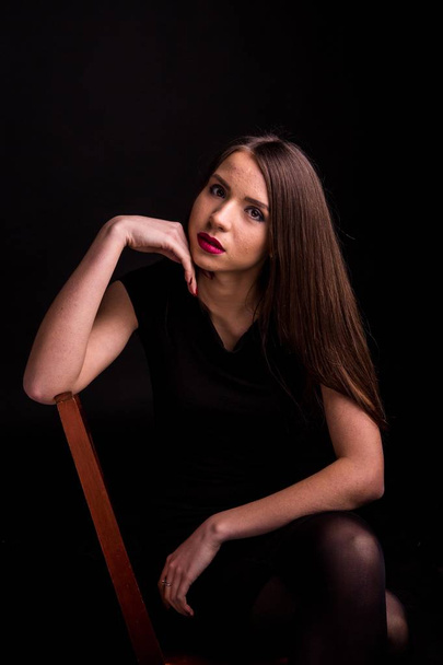 Portrait of a beautiful young woman in a black dress with a cool makeup and good skin. Studio, black background. - Foto, Bild
