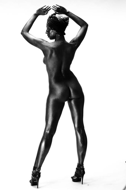 Naked woman painted in black on a white background in the studio - Foto, afbeelding