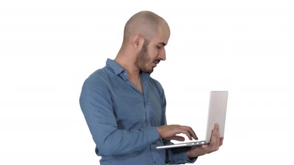 Young middle eastern businessman, standing and typing on laptop when holding it in his hands on white background. - Felvétel, videó