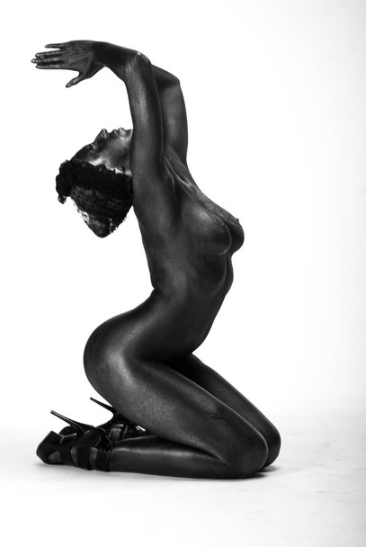 Naked woman painted in black on a white background in the studio - Fotografie, Obrázek