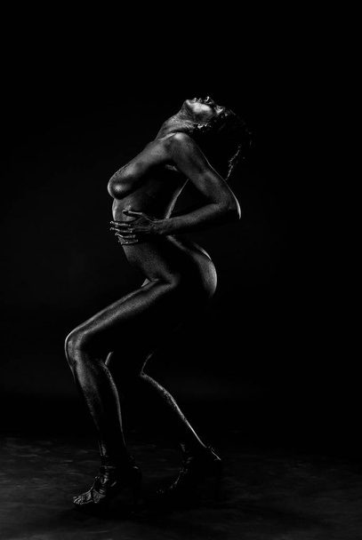 Naked woman painted in black on a white background in the studio. - Photo, image