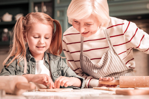 Concentrated kid spending time with granny in kitchen - Photo, Image