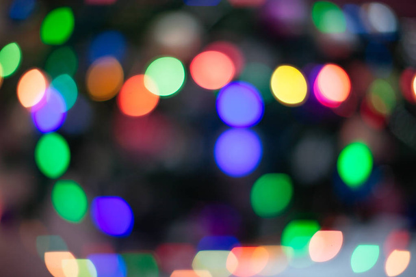 The Christmas tree is lit in different colors. Blurred background of the new year holiday - Foto, Imagen