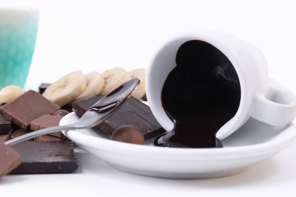 chocolate negro derretido con una textura cremosa derramada de una taza a
 - Foto, Imagen