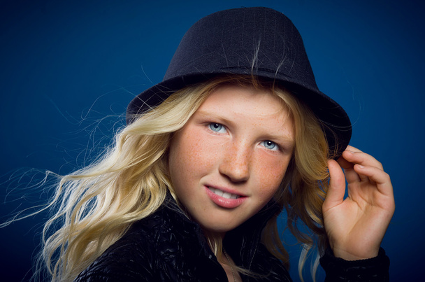 Girl smiling holding on to the hat and looking at the camera - Fotoğraf, Görsel