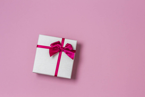 Gift present box with satin bow on light pink background, top view - Fotó, kép