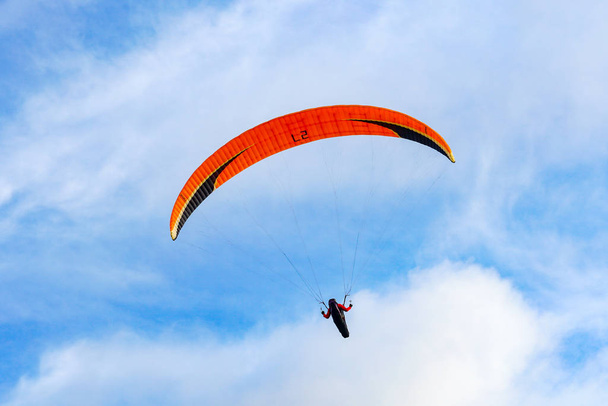Man doing sport (Para-glider). Man paragliding in the clouded sky. Paragliding is an extreme sport and recreation. Torrey Pines Gliderport. San Diego. California, USA.  - Foto, afbeelding