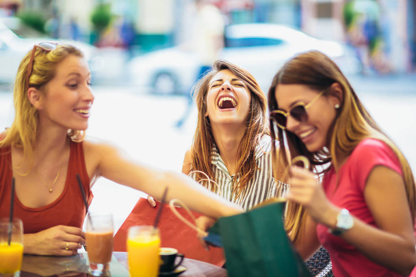 Drei junge Frauen nach einem Einkauf in einem Café - Foto, Bild