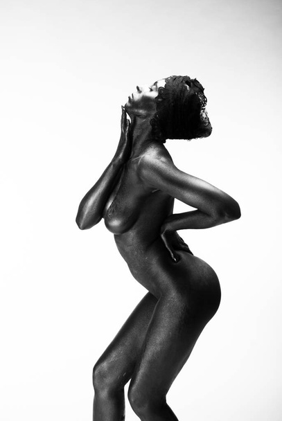 Naked woman painted in black on a white background in the studio - Foto, Bild