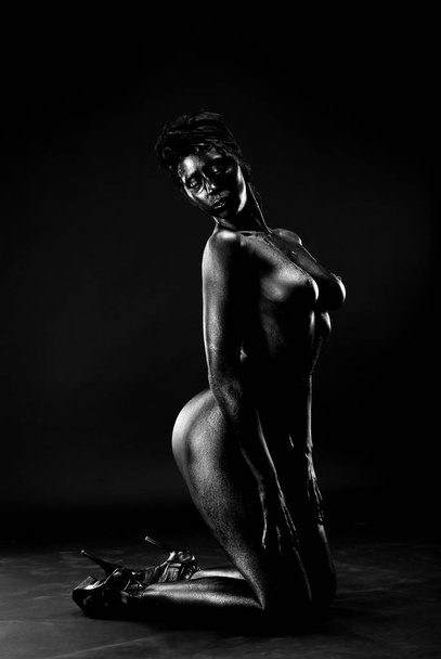 Naked woman painted in black on a white background in the studio. - Foto, immagini