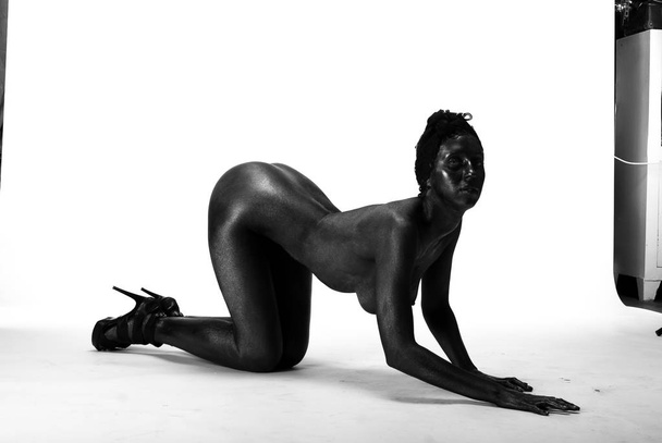 Naked woman painted in black on a white background in the studio - Foto, Imagen
