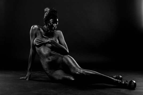 Naked woman painted in black on a white background in the studio. - Photo, Image