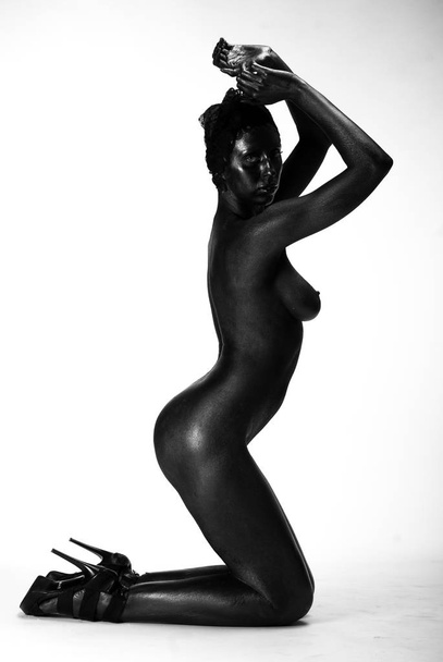 Femme nue peinte en noir sur fond blanc en studio
 - Photo, image