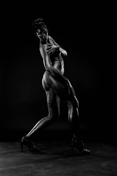 Naked woman painted in black on a white background in the studio. - Foto, Bild