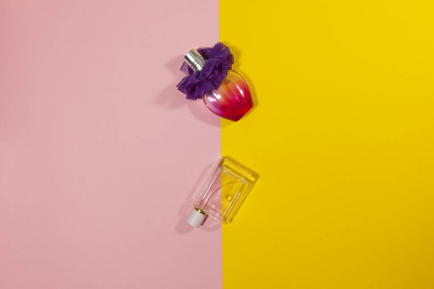 Két palack fektetése rózsaszín és sárga felületre - Fotó, kép