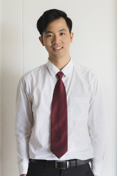 Молодой азиатский бизнесмен в черном костюме стоит
 - Фото, изображение