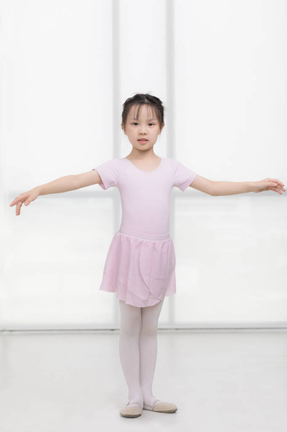 Roze gekleed aziatisch meisje in een ballet pose - Foto, afbeelding